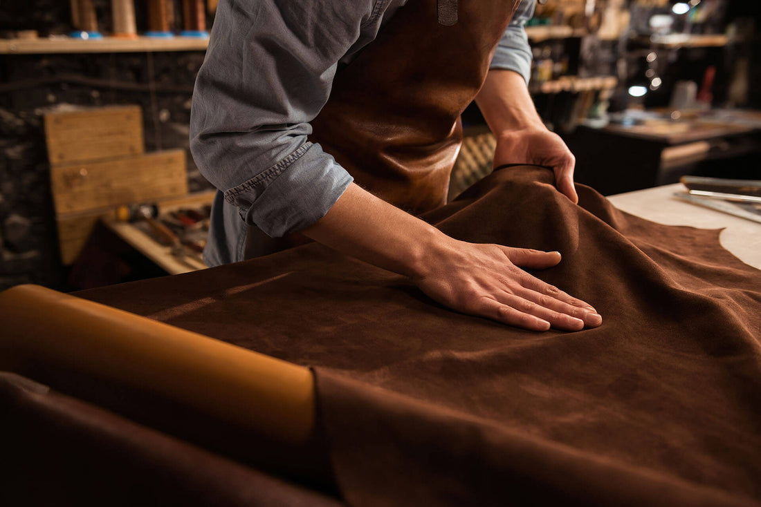 Artisan trabajando con cuero auténtico sostenible en un taller, destacando su textura y calidad.